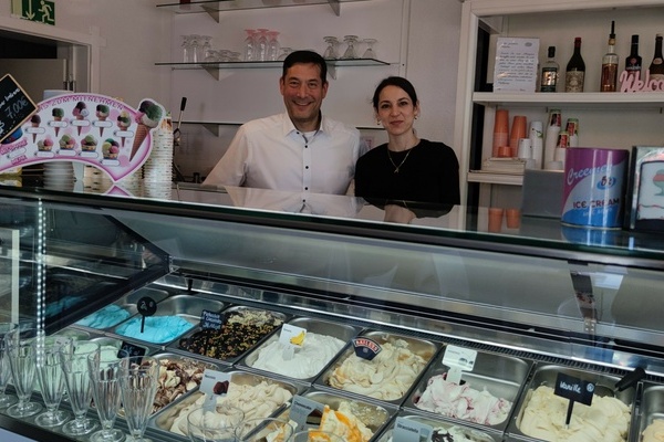 Brgermeister Hollemann und Frau Gler Cicco-Sander, Inhaberin der Eisdiele, stehen hinter der mit verschiedenen Eissorten gefllten Eistheke