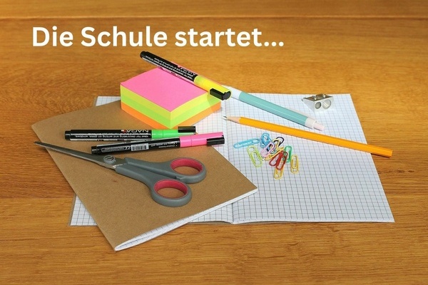 Die Schule startet ... Schulutensilien auf einem Tisch, weie Schrift auf hlzernem Untergrund