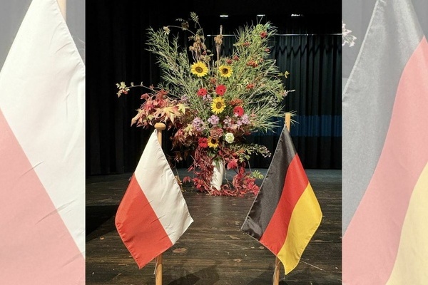 Gro&szlig;es, buntes Blumengesteck im Vordergrund die polnische und die deutsche Flagge. Foto: Gemeinde Denzlingen