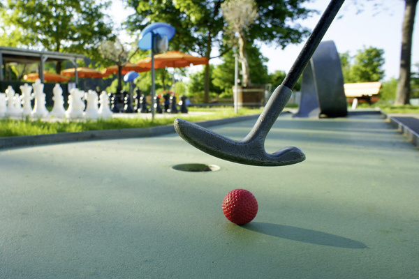 Minigolfschl&auml;ger mit Minigolfball auf einer Minigolfbahn